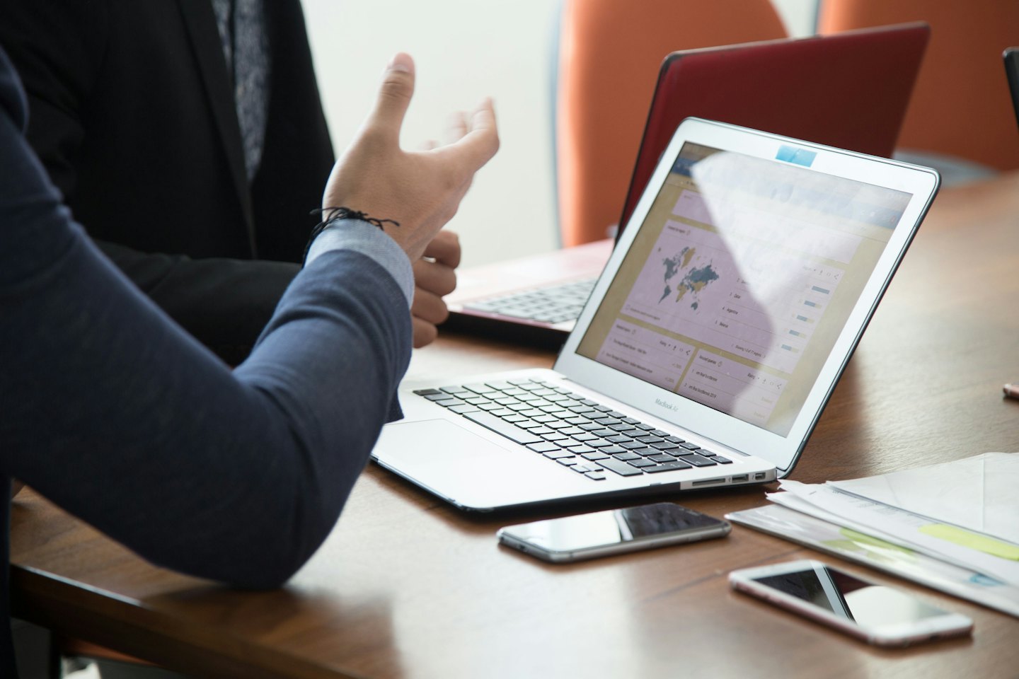 Business professionals discuss data on a laptop at a conference table.